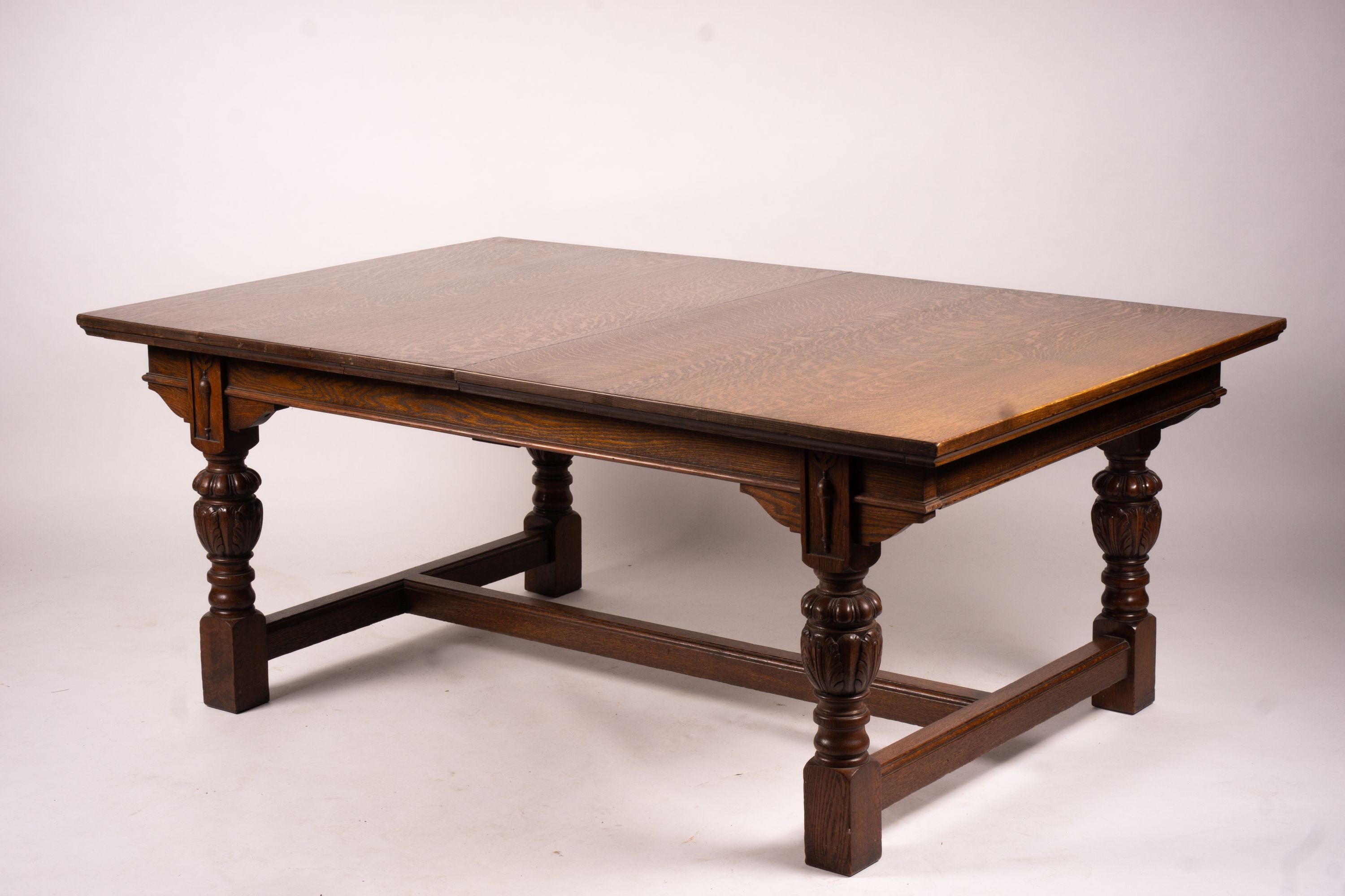 A 17th century style carved rectangular oak extending dining table with 'H' stretcher, 300cm extended, two spare leaves, width 121cm, height 75cm